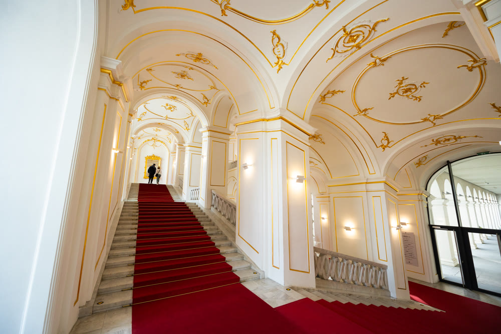 Grand staircase of Bratislava Castle with red carpet and marble balustrade
