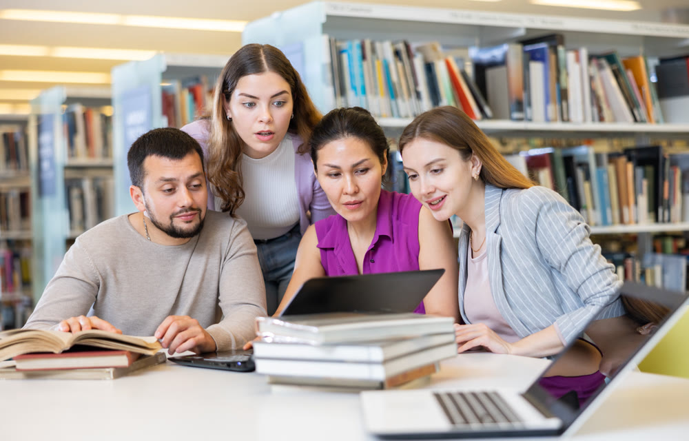 Friendly group of students preparing together for exam in modern university library
