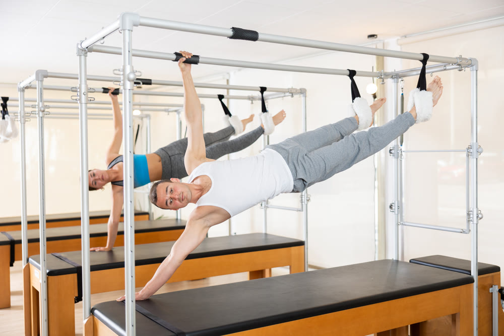 Man performing side hanging exercise on Pilates Cadillac