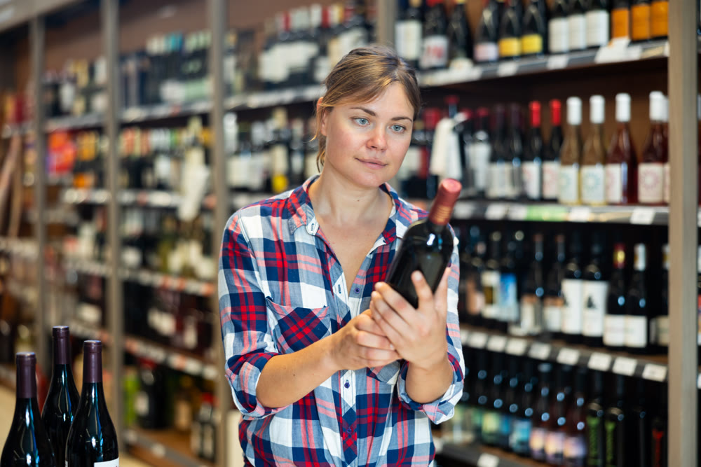 Woman choosing alcoholic drinks in grocery store