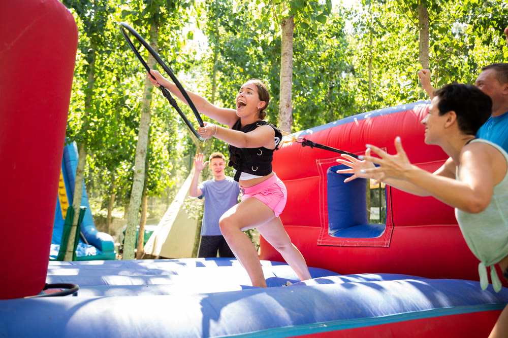 Young woman with hoop playing tug of war game with opponent outdoors
