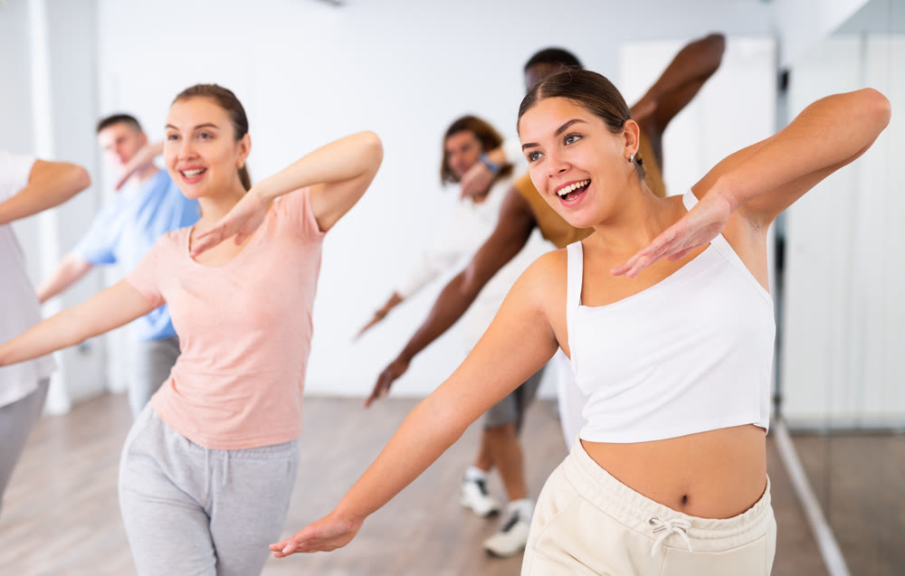 Women and man learning swing steps at modern dance class