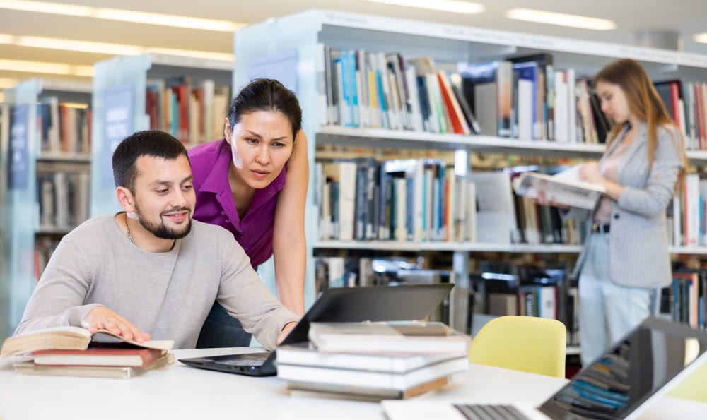 Friendly couple studying together at library