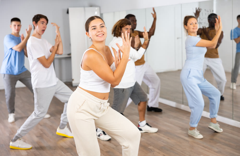 Group of active women and men practicing energetic dance in modern dance studio