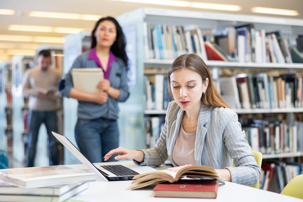 Young woman working on laptop at library