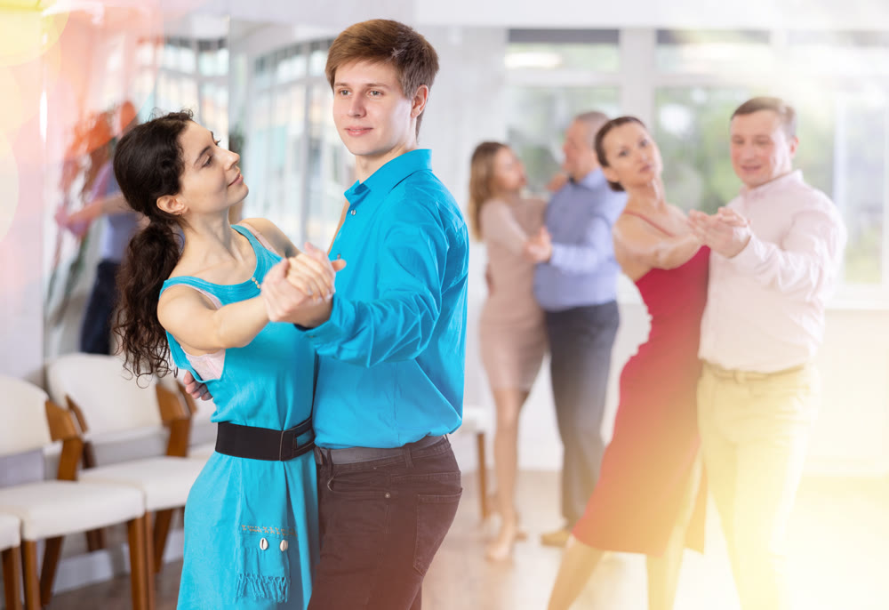 Portrait of adult pairs of different ages enjoying tango in modern dance hall together