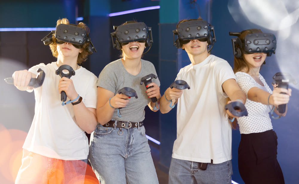 Emotional young girls and guys in VR headsets immersed in game