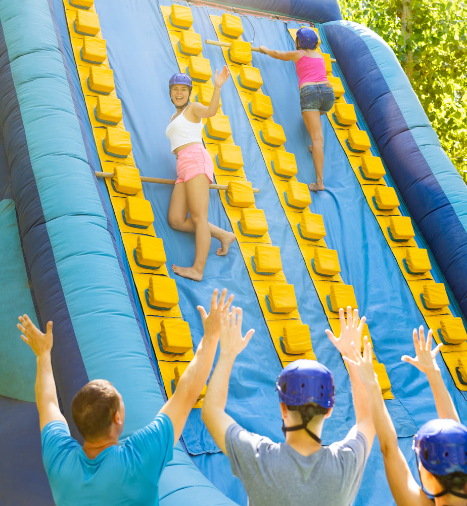 Women using sticks to reach top of slide in adventure park