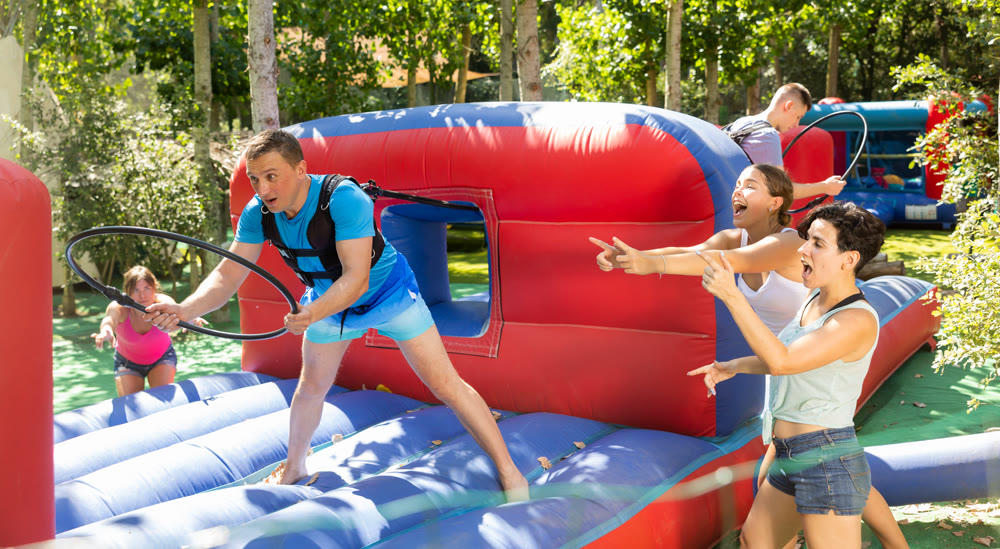 Cheerful man competing to collect hoops on inflatable playground