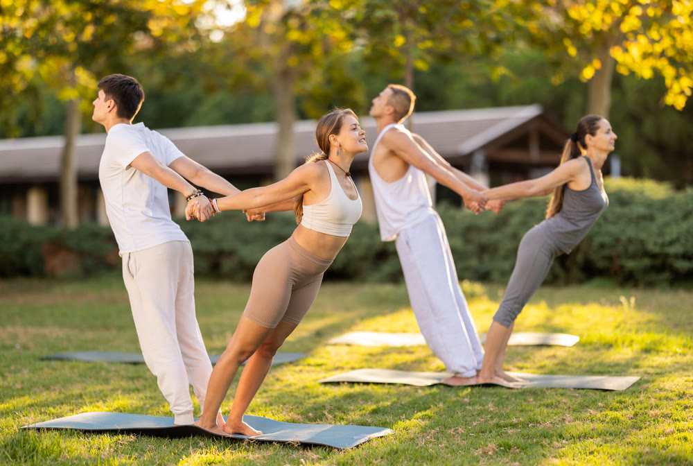 Guy and girl practice pair yoga doing Backbend Balance pose asana