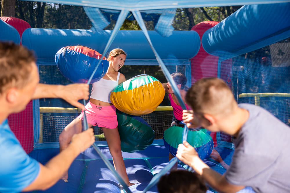 Women holding soft pillows and fighting in adventure park
