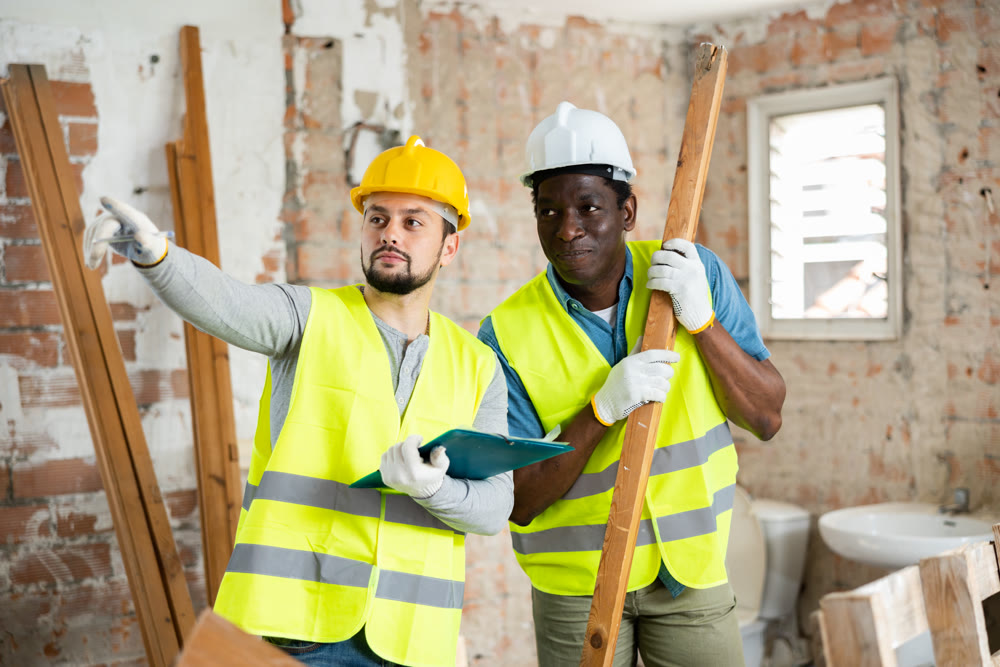 Two builders take notes, evaluating the work plan