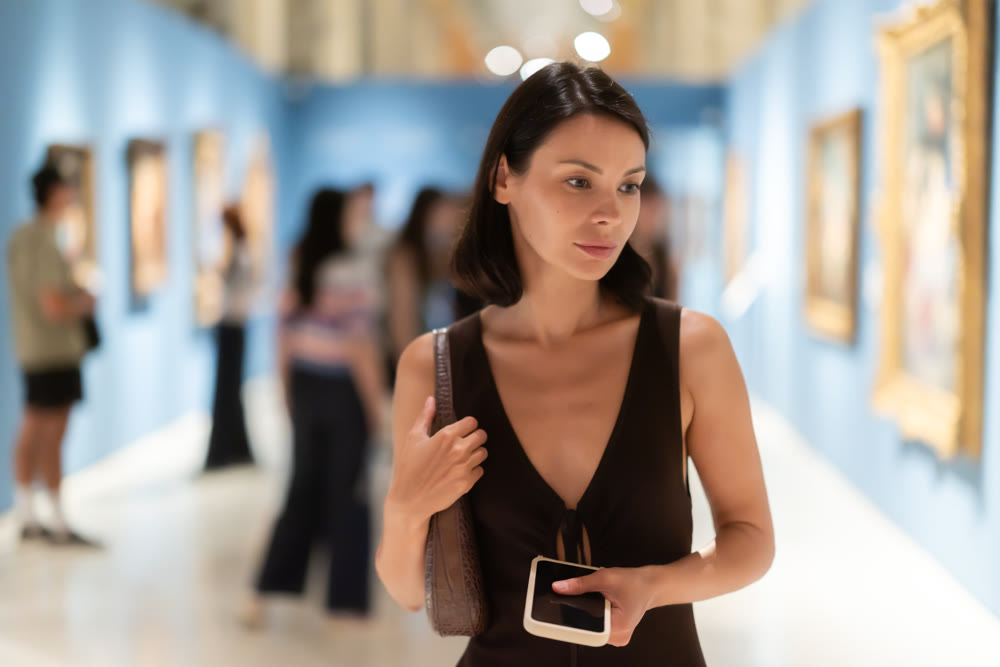 Young woman in summer clothes looking at paintings in museum