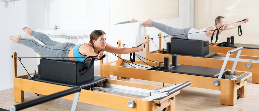 Girl in lying position is engaged in stretching muscles of legs and buttocks on simulator