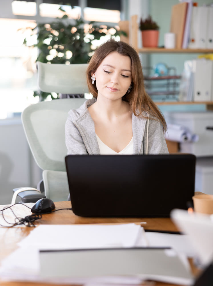 Young woman sitting at desk and working on laptop