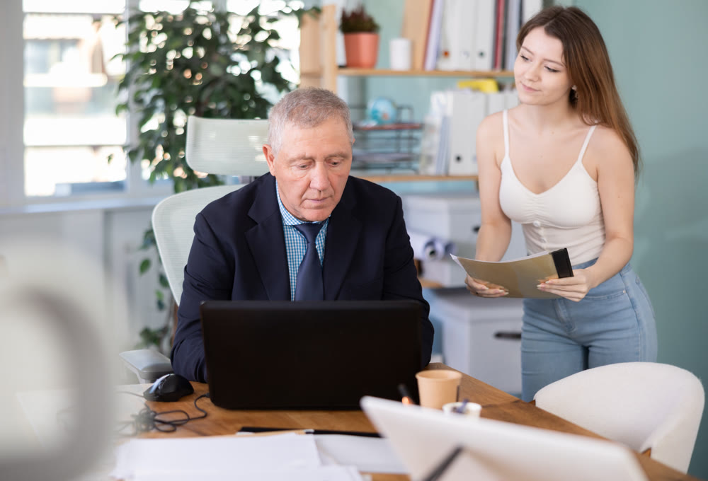 Female secretary brings folder with documents for company director to sign