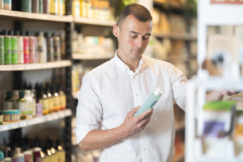 Interested male shopper choosing organic care products in eco store