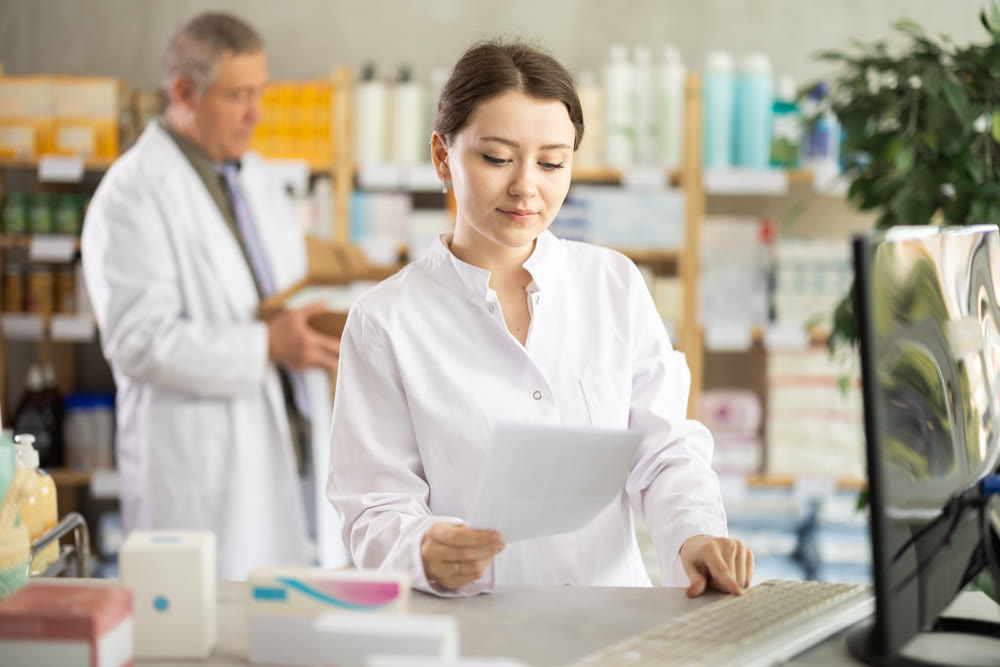 Female pharmacist checking prescription on computer