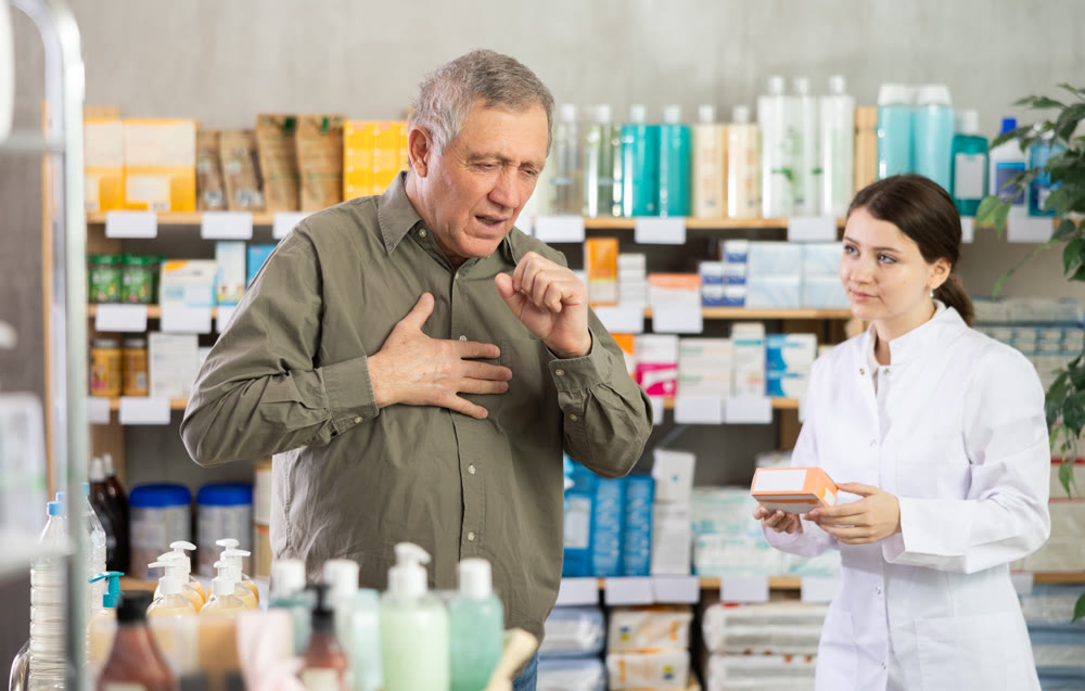 Man with cough choosing pills with help of pharmacist