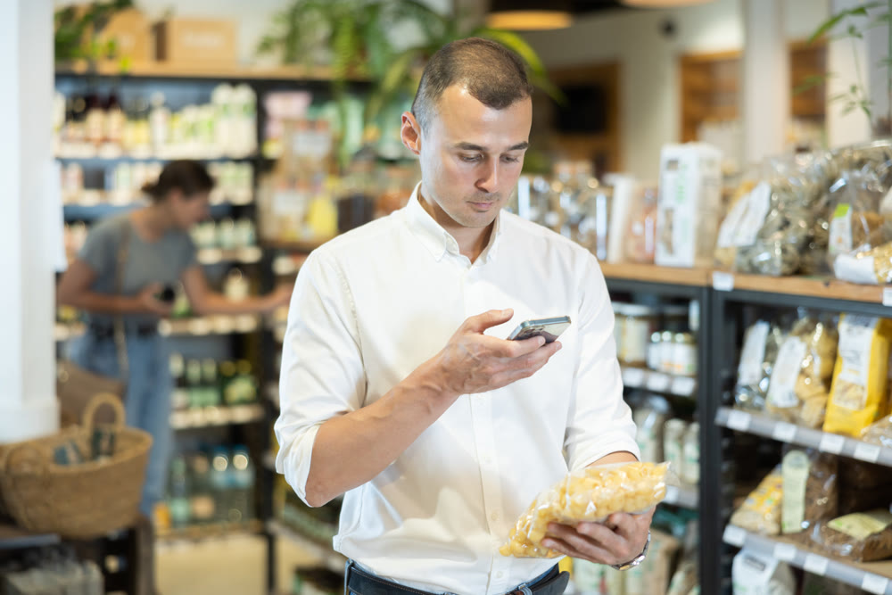 Man scanning bag of pasta with smartphone in grocery store