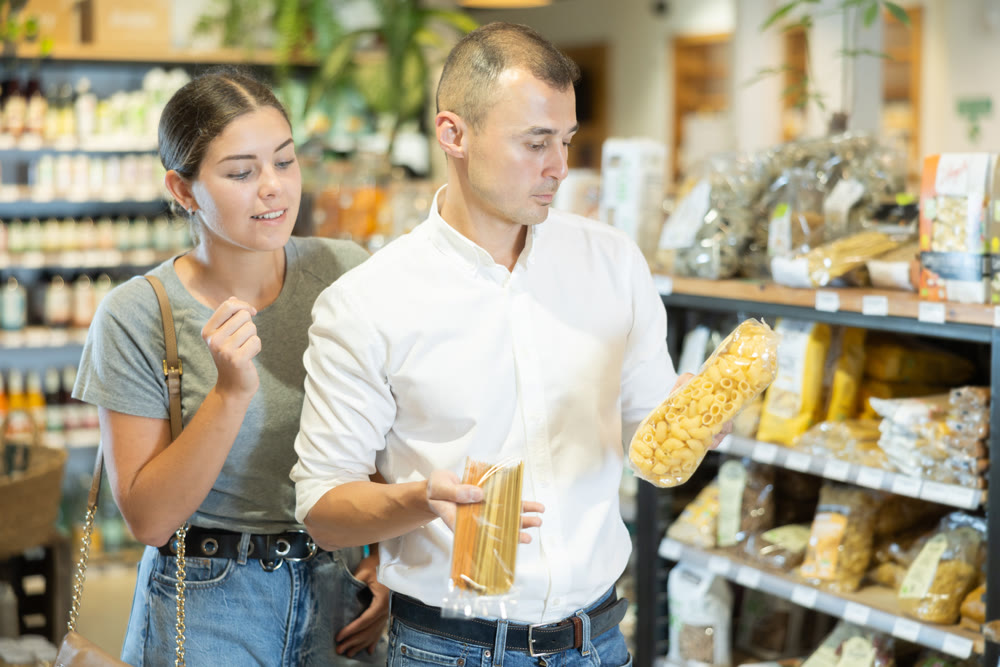 Young couple buying pasta in large grocery store