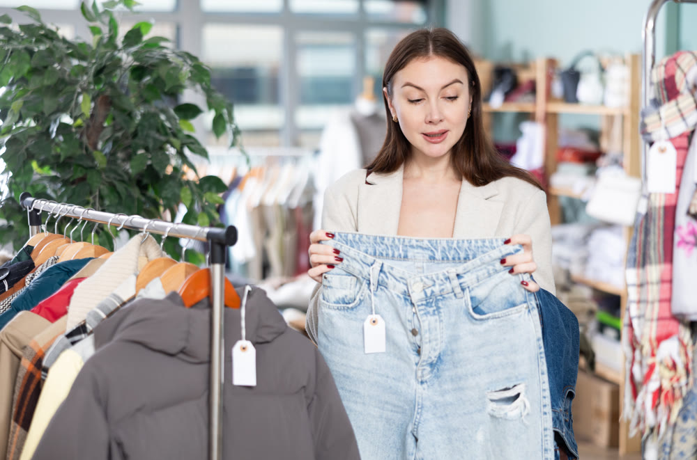 Young woman choosing jeans in clothing store