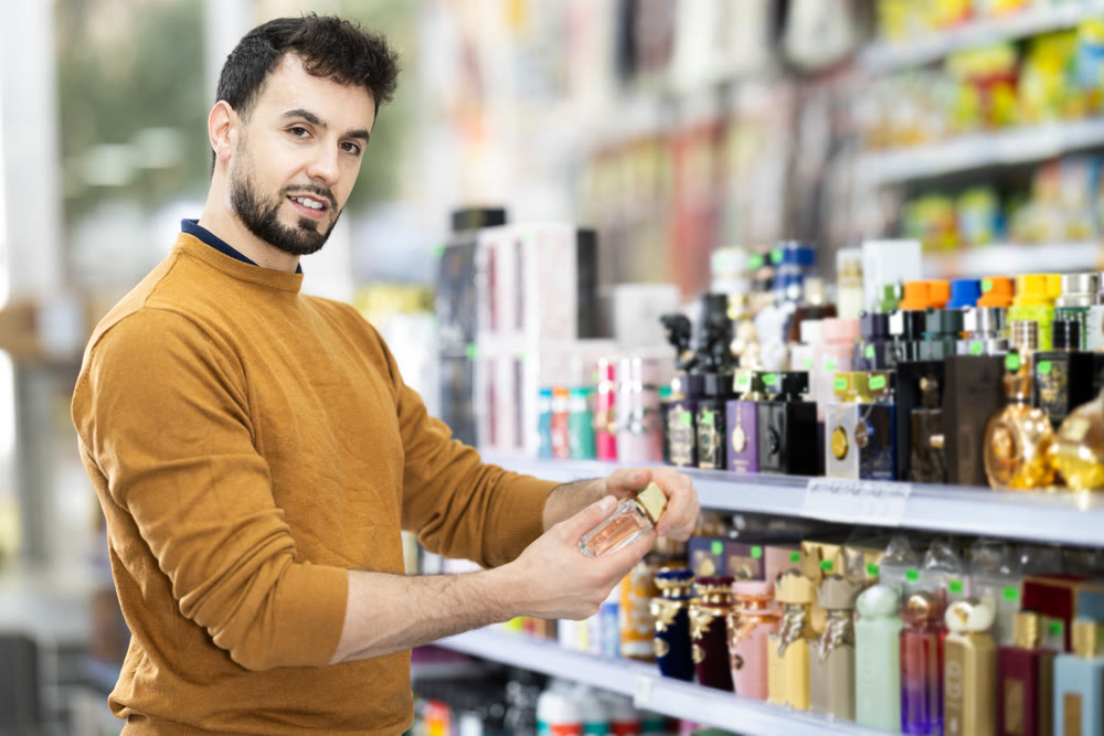Male buyer choosing bottle of toilet water in perfume shop
