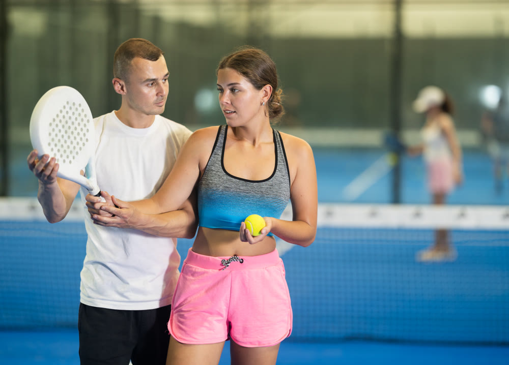 Man teaching young woman to hold racket