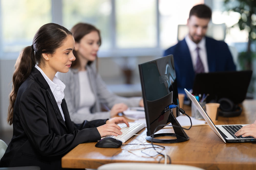 Focused young woman working on laptop during busy corporate session