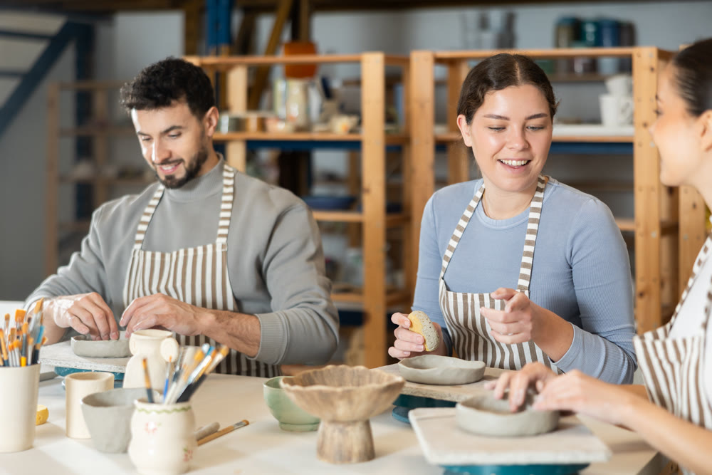Three pottery workshop workers sculpt from clay, form final product