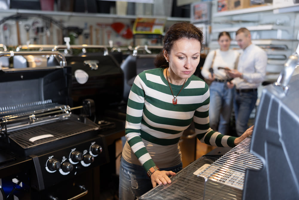 In store, woman inspects mobile grill, buys barbecue device