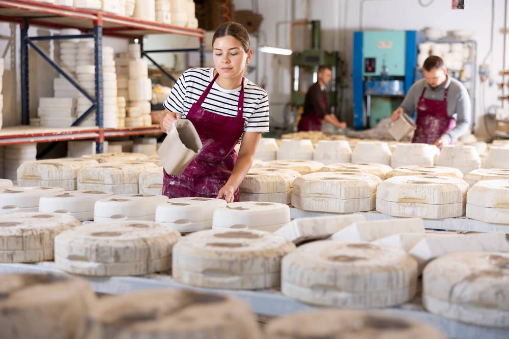 Female artisan pouring slip into casting molds in workshop