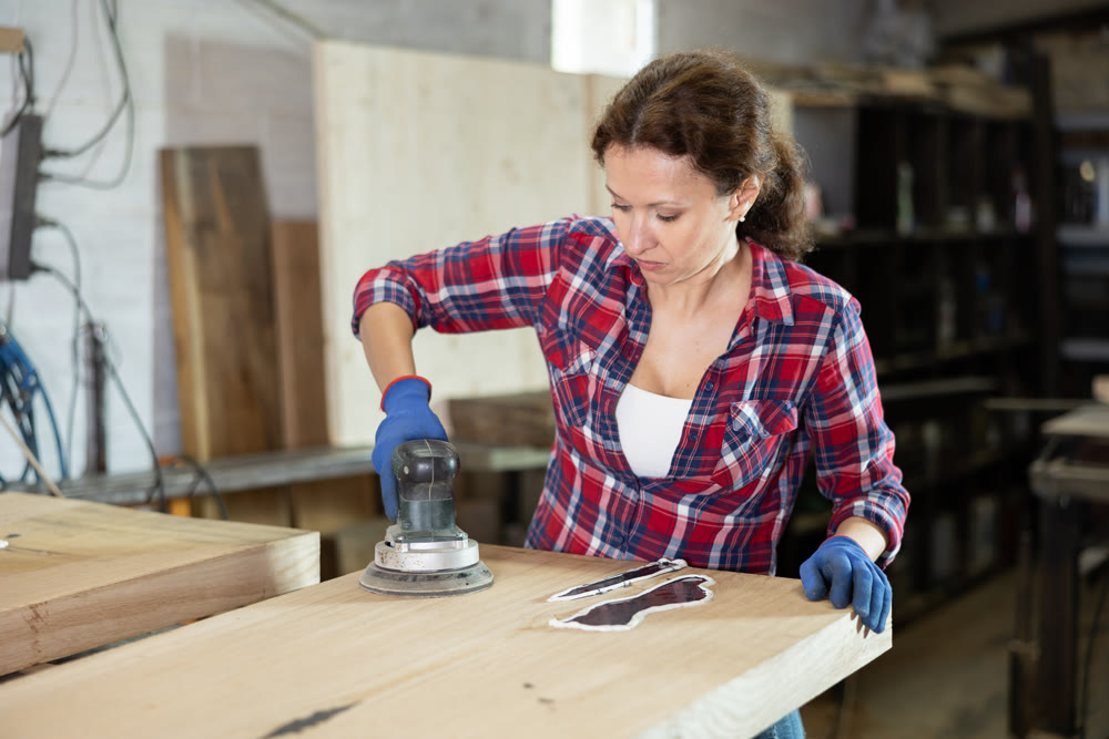 Woman sanding a wooden board using sanding machine