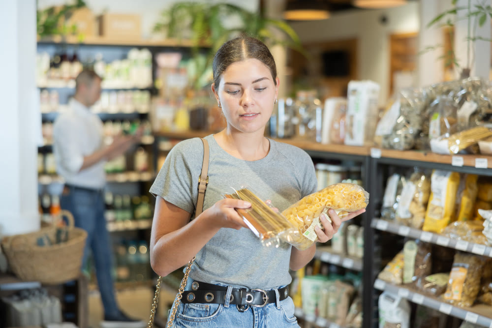 Girl choosing pasta in natural grocery section of supermarket