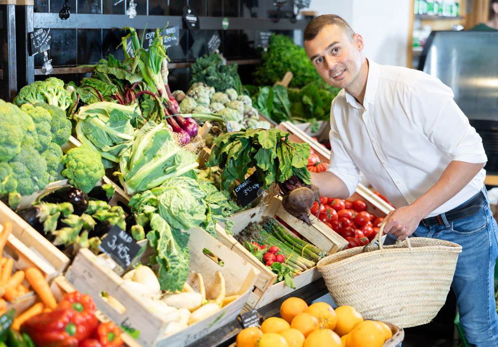 In vegetable department of bio supermarket, male customer took bunch of beets from window