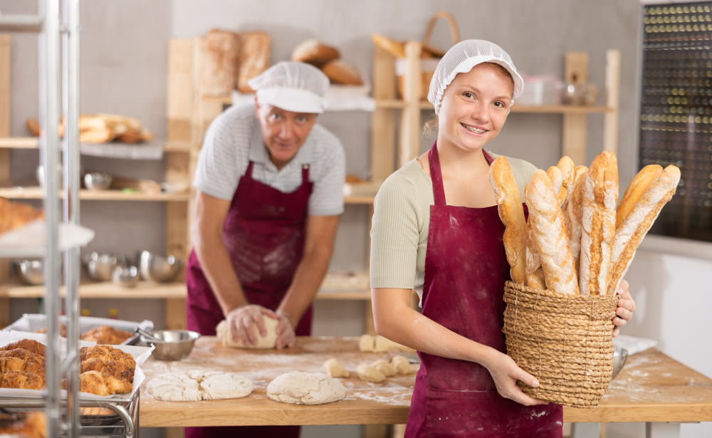 Young woman baker with basket of baguettes