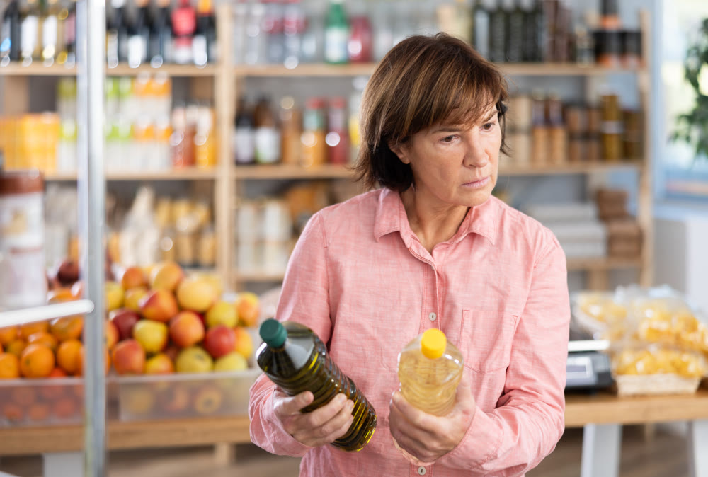 Woman chooses vegetable oil while shopping in grocery supermarket