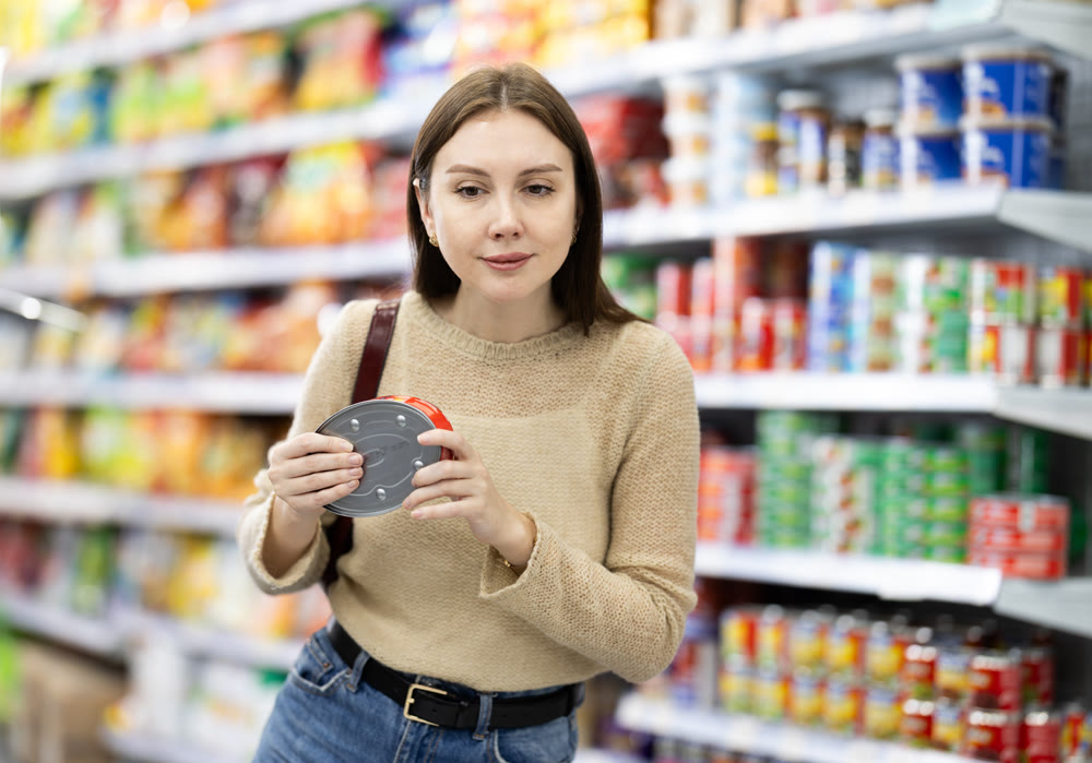 Girl in supermarket search and select product tin can