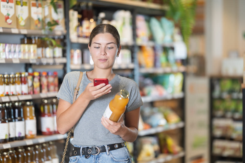 Female shopper scanning QR code on juice bottle in store