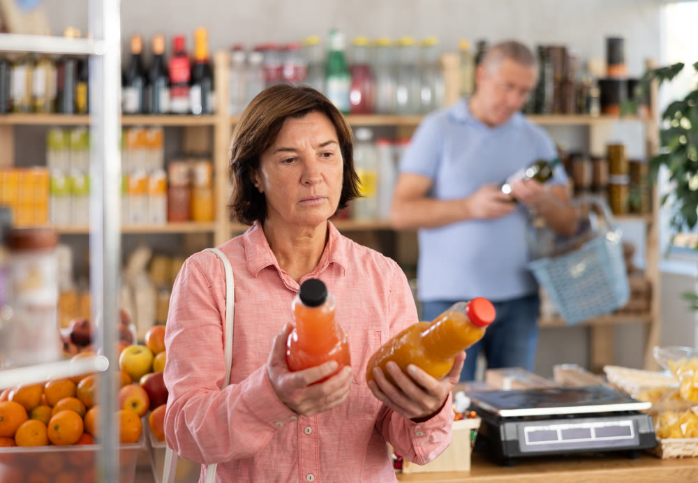 Elderly woman chooses peach and grapefruit juice