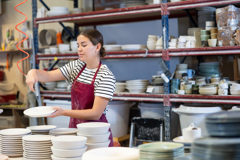 Young woman paints blanks of ceramic products
