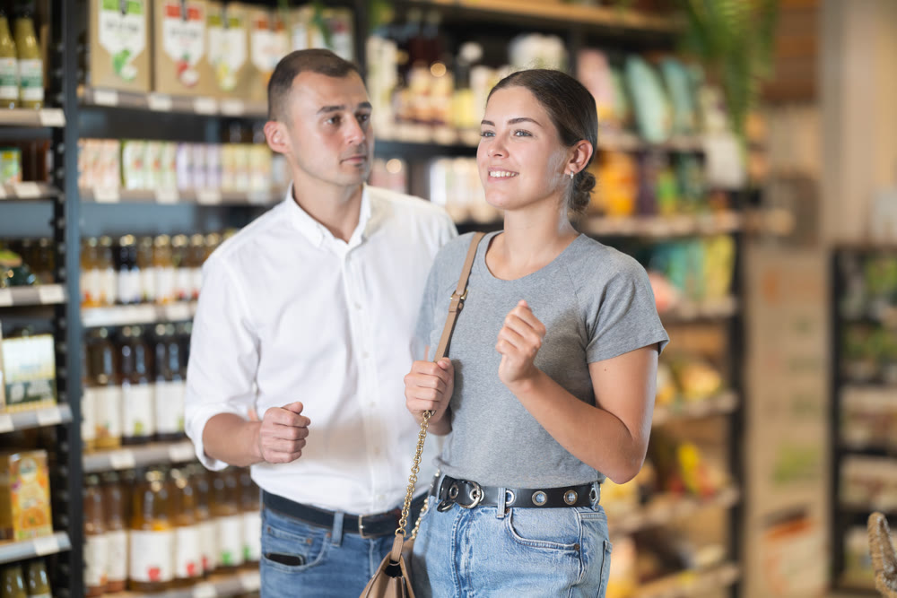 Married couple stands in middle of hall and looks at something in distance of trading floor