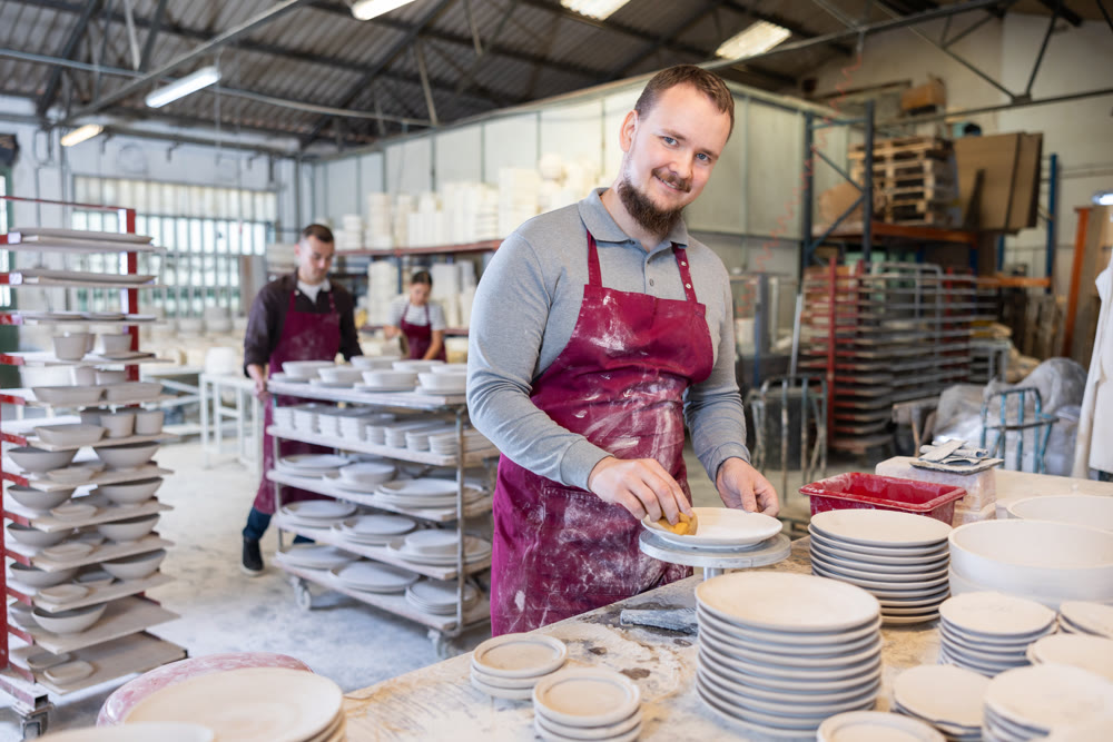 Young man cleaning blanks of ceramic products