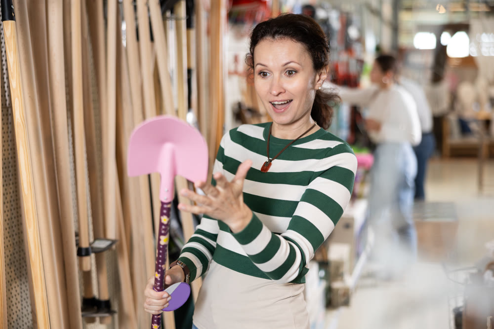 Adult woman choosing shovel in store