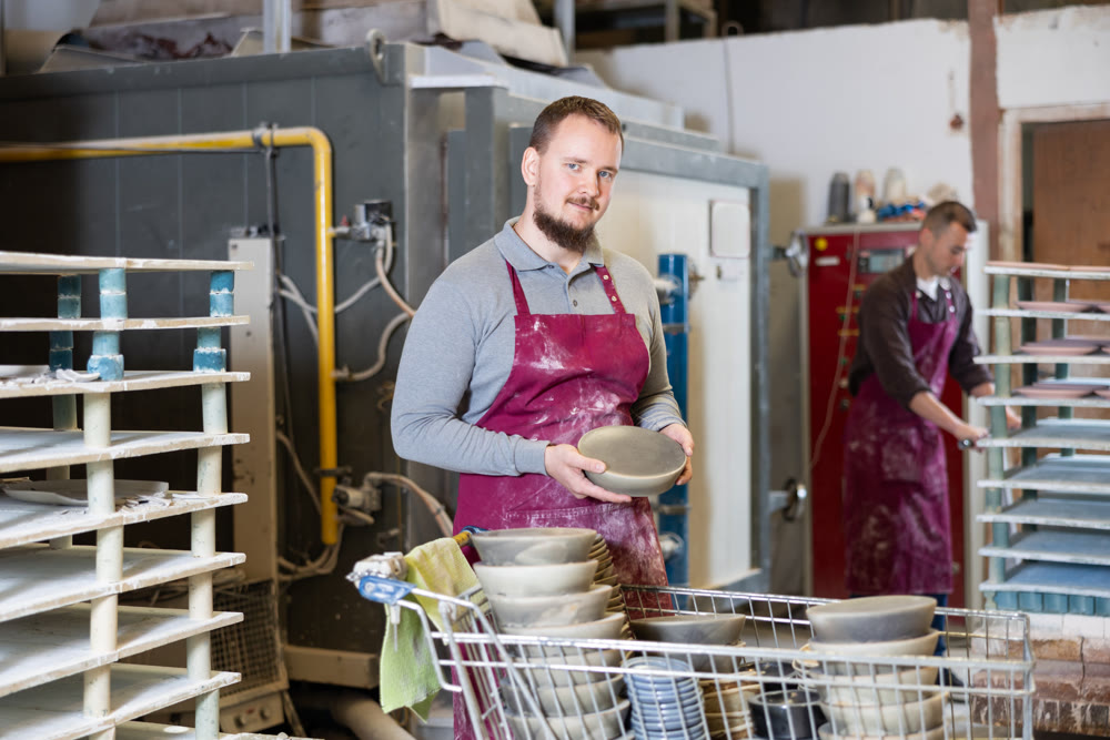 Successful potter displaying handcrafted plate in artisanal pottery studio