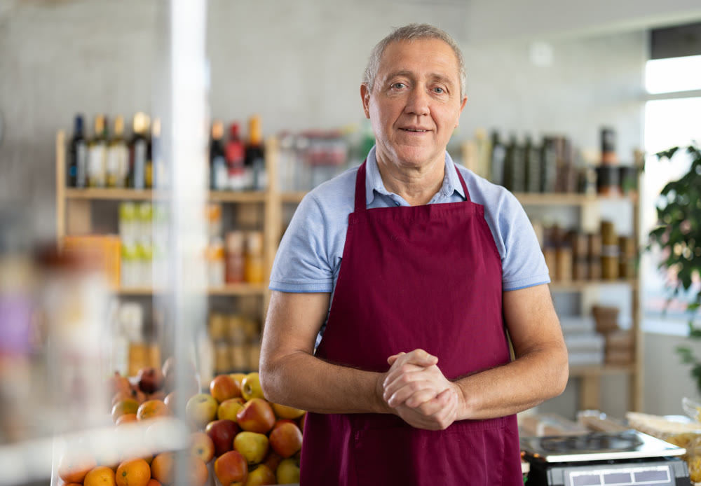 Elderly man seller at counter in grocery store