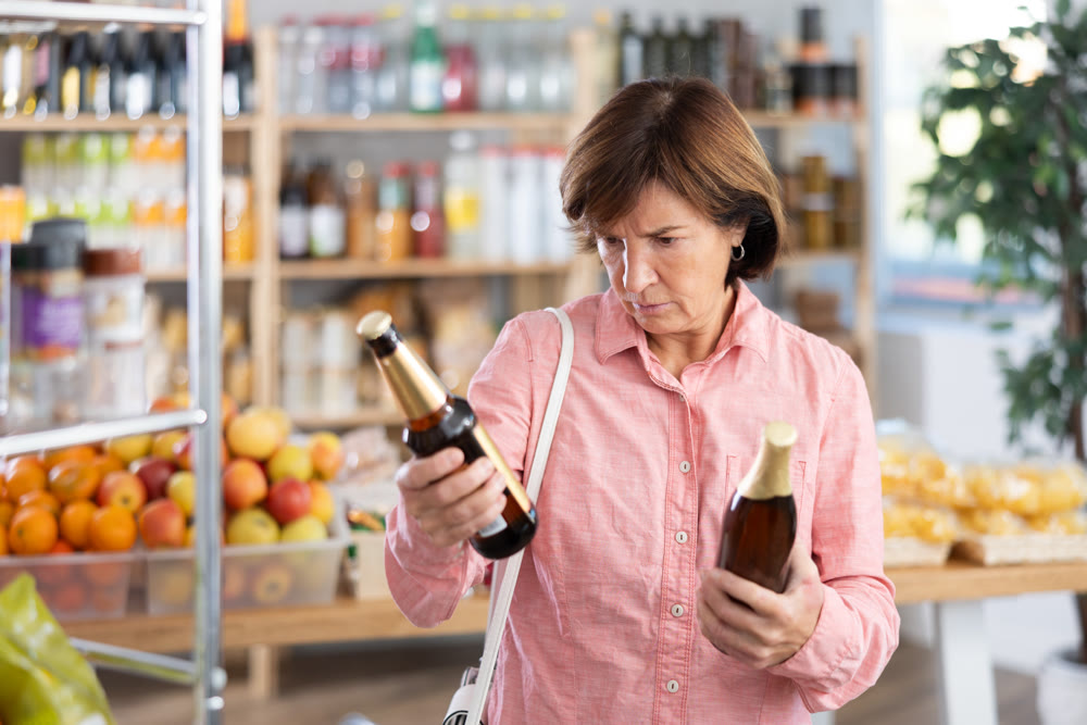 Choose alcohol in supermarket - woman chooses what beer to buy in alcohol section of store