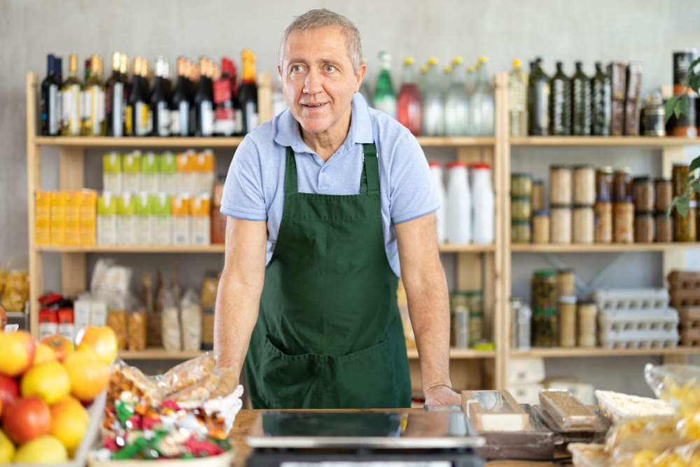 Elderly man seller at counter in grocery store