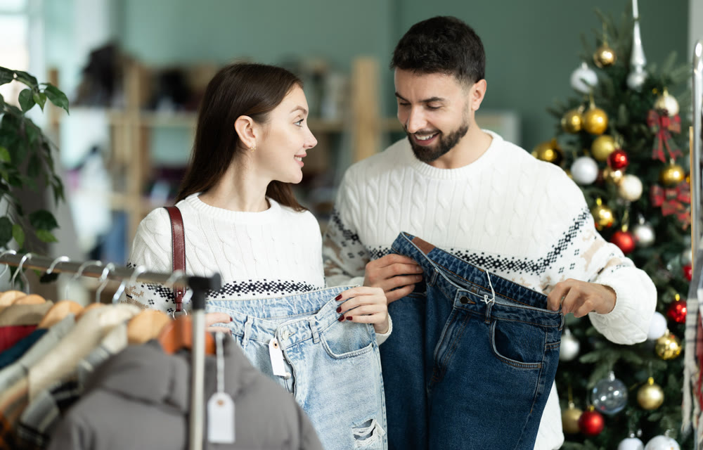 couple chooses comfortable jeans against the background of a Christmas tree in a store