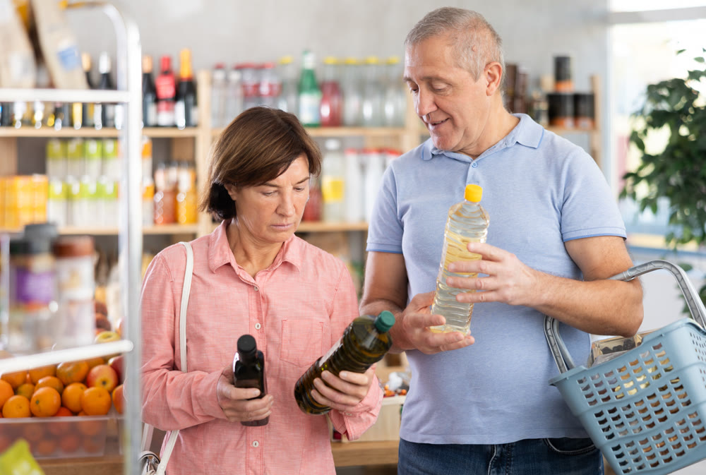 Elderly man and woman choose vegetable oil and olive oil products together in grocery supermarket